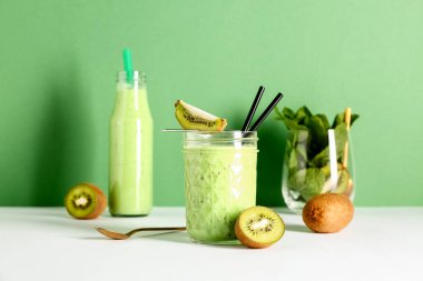 Bardak ve beyaz masada naneli taze kivili smoothie.