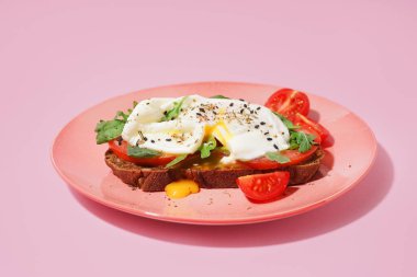 Pembe arka planda yumurtalı lezzetli bir sandviç tabağı.