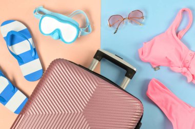 Renkli arka planda bavul ve plaj aksesuarlarıyla kompozisyon