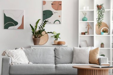 Kanepesi, raf ünitesi ve çiçekleri olan aydınlık oturma odasının içinde.