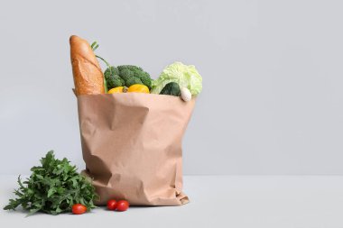 Gri arka planda taze sebzeli kağıt alışveriş torbası.
