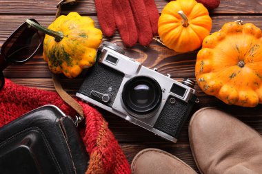 Ahşap arka planda kadın kıyafetleri, aksesuarlar ve balkabakları olan kompozisyon, yakın plan.