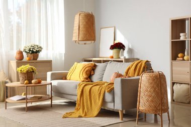 Gri kanepe ve kahve masasında kasımpatı çiçekleri olan rahat bir oturma odası.