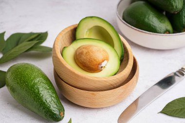 Beyaz arka planda taze olgun avokadolarla dolu kaseler.