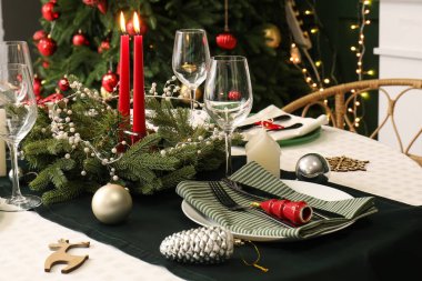 Noel çelengi ve yanan mumlarla süslü masa seti, yakın plan.