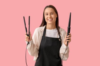 Pembe arka planda saç maşası ve ütüsü olan kadın kuaför.