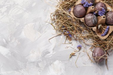 Çiçekli Paskalya yumurtaları ve gri arka planda saman.