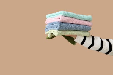 Kahverengi arka planda temiz havluları olan bir kadın el.