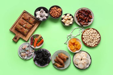 Yeşil arka planda Ramazan için farklı Doğu tatlıları ve tasbih çerçevesi