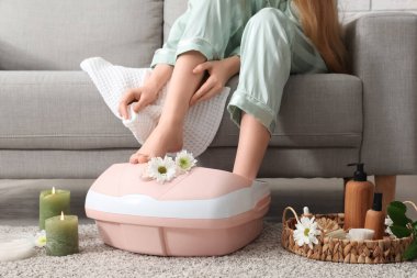 Kaplıca malzemeleri taşıyan bir kadın evde ayak banyosu yapıyor.