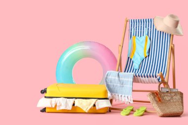 Elbiseli çanta, plaj aksesuarları ve pembe arka planda iskemle.