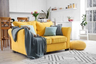 İçinde çiçekler, sarı kanepe ve ekoseli modern mutfak.