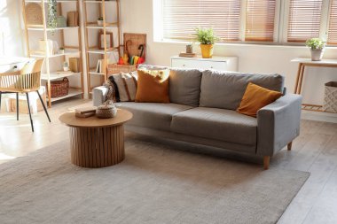 Oturma odasının içinde kanepe, bitki ve raf üniteleri var.