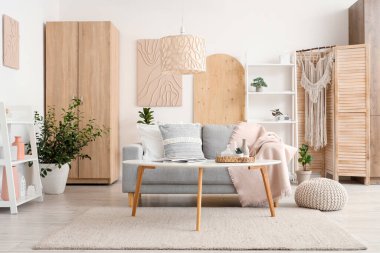 Koltuğu, çiçekleri, raf ünitesi ve sehpası olan şık bir oturma odası.