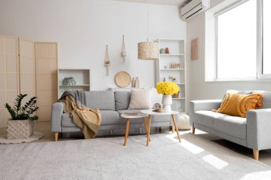 Yumuşak kanepe, kahve masası ve hafif oturma odasında narsisli çiçekler.