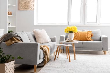 Rahat koltuklar, kahve masası ve vazo açık oturma odasında narsisli çiçekler.