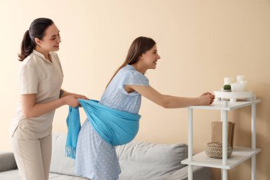 Genç hamile kadın evde doğum koçu tarafından masaj yaptırıyor.