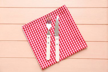 Bej ahşap arka planda peçete, çatal ve bıçaklı masa ayarları