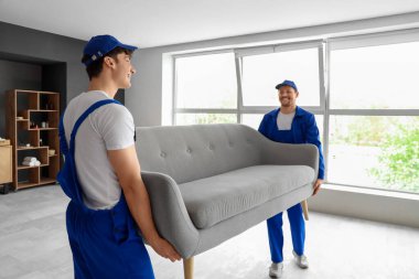 Loaders carrying couch in room