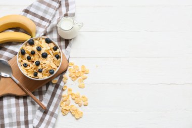 Peçete, ahşap tahta, muz, mısır gevreği ve böğürtlenli kase beyaz ahşap arka planda