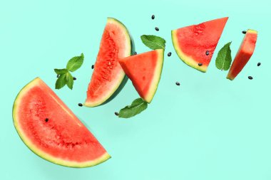 Uçan taze karpuz parçaları tohumlar ve turkuaz arka planda nane şekeri.