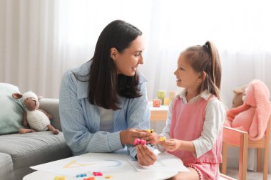 Ofiste küçük bir kızla çalışan kadın konuşma terapisti.