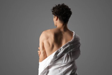 Gri arka planda beyaz gömlekli kaslı genç adam.