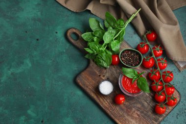 Yeşil arka planda fesleğen ve biberli domates sosu kavanozu.