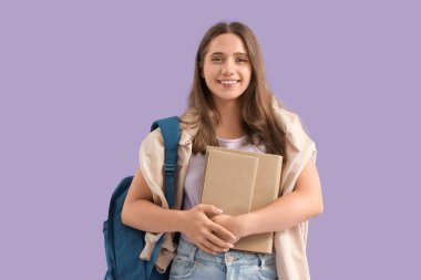 Sırt çantası ve mor arka plan kitapları olan mutlu bir kız öğrenci.