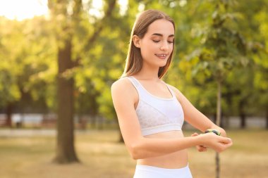 Sportif genç bayan parkta antrenmandan sonra nabız sayıyor.