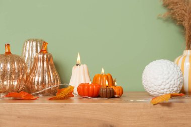 Balkabağı şeklinde mumlar ve sonbahar yaprakları evdeki yeşil duvarın yanında klozette yanıyor.