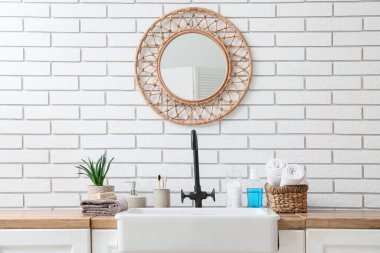 Lavabo ve banyo aksesuarları banyodaki beyaz tuğla duvarın yanında.