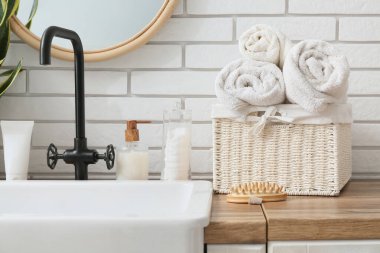 Lavabo ve banyo aksesuarları banyodaki beyaz tuğla duvarın yanında.