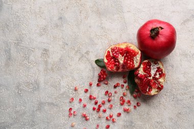 Gri zemin üzerinde yaprakları ve tohumları olan taze nar.