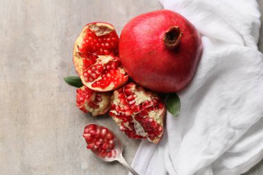 Taze olgun nar ve kaşık, gri arka planda tohumlar.