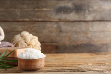 Tahta arka planda bir kase doğal vücut fırçası, sabun ve banyo süngeri.