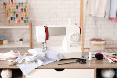 Atölyede kumaş ve terzi malzemeleri olan modern dikiş makinesi.
