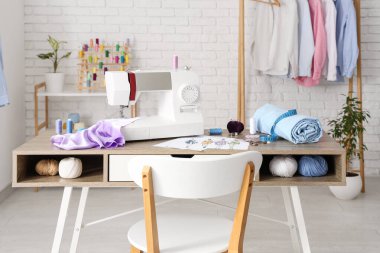 Terzinin dikiş makinesi, farklı malzemeler ve atölyedeki elbise rafı.