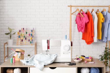 Kot şortlu modern dikiş makinesi ve atölyedeki terzi malzemeleri.