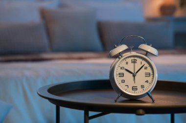 Geceleri karanlık yatak odasındaki masada çalar saat, yakın plan.