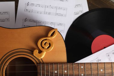 Gitar, keman anahtarı, vinil disk ve müzik kağıtları, yakın plan.