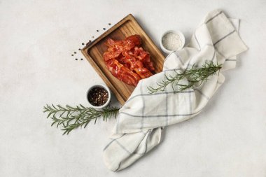 Kızarmış pastırma pastırmalı ahşap tahta, biberiye ve beyaz arka planda bir kase biber.