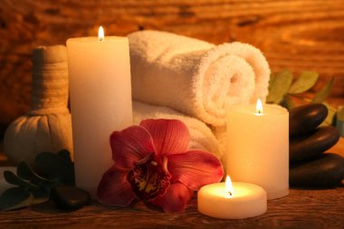 Koyu ahşap arka planda yanan mumlar ve okaliptüs dallarıyla güzel bir spa kompozisyonu.