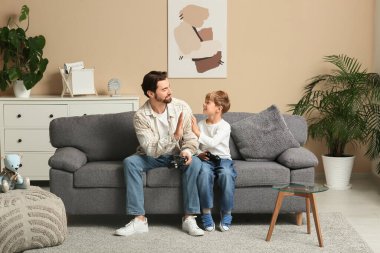 Baba ve küçük oğlu evde video oyunu oynuyorlar. Babalar Günü.