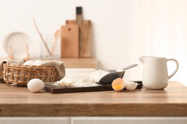 Mutfak tezgahında hamur hazırlamak için kepçe kepçe, yumurta, buğday dikenleri ve bir sürahi sütle un.