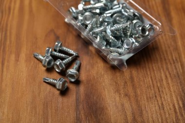 Kahverengi ahşap arka planda kısa vidaları olan paket, yakın plan