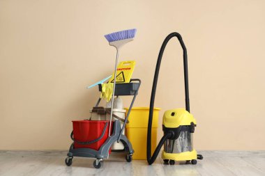 Temizlik malzemeleri ve bej duvarın yanında elektrikli süpürge olan bir tramvay.