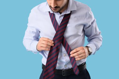 Mavi arka planda kravatlı genç işadamı, yakın plan