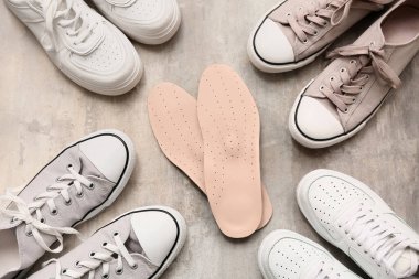 Gri grunge arka planında ortopedik tabanlı farklı ayakkabılar.