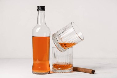 Bardaklar ve beyaz arka planda puro olan bir şişe rom.